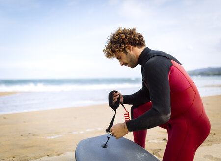 Spanien, Asturien, Colunga, Surfer bereitet Bodyboard am Strand vor - MGOF000837
