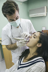 Zahnarzt, der den Mund eines Patienten mit einer intraoralen Kamera untersucht - ABZF000129