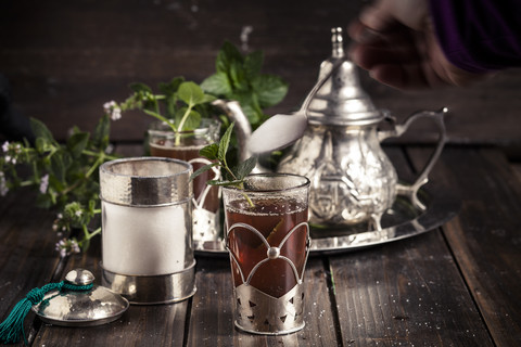 Zucker in den traditionellen nordafrikanischen Tee mit frischen Minzblättern gießen, lizenzfreies Stockfoto
