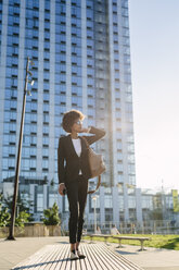 USA, New York City, businesswoman standing outdoors at sunset - GIOF000251