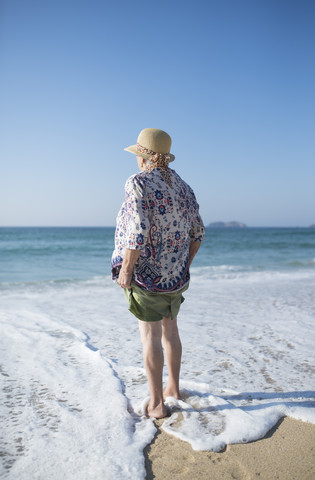 Spanien, Ferrol, Rückenansicht einer am Strand stehenden älteren Frau, lizenzfreies Stockfoto