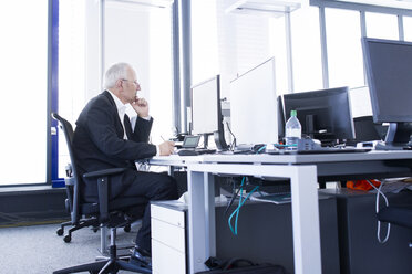 Businessman in open space office working at desk - SGF001906