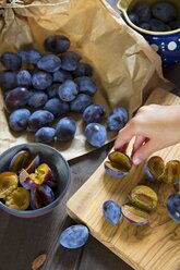 Plums on chopping board, pitting - YFF000456