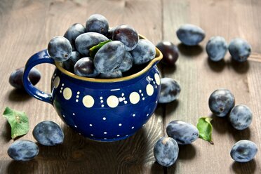 Plums on wood and in blue jar - YFF000461