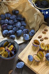 Plums on chopping board, pitting - YFF000466