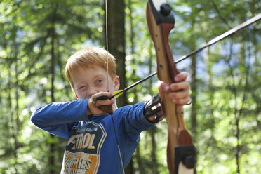Porträt eines Jungen mit Pfeil und Bogen in einem Abenteuerpark - JEDF000251