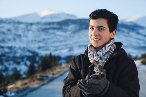 Jugendlicher in Winterkleidung, verschneite Berge im Hintergrund - BZF000265