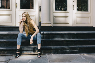 USA, New York City, nachdenkliche junge Frau sitzt auf einer Treppe vor einer Eingangstür - GIOF000257