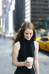 USA, New York City, Porträt einer lächelnden jungen Frau mit Kaffee zum Mitnehmen - GIOF000268