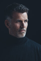 Portrait of man wearing black turtleneck in front of black background - CHAF001474