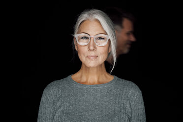 Porträt einer grinsenden Frau mit Brille vor einem schwarzen Hintergrund - CHAF001488