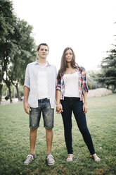 Young couple in love standing on a meadow in a park holding hands - JRFF000117