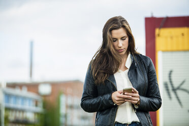 Deutschland, Münster, junge Frau schaut auf ihr Smartphone - TAMF000285