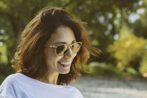 Porträt einer lächelnden Frau mit braunem Haar und Sonnenbrille, lizenzfreies Stockfoto