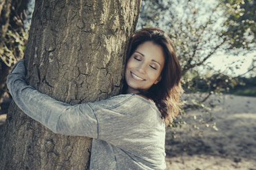 Portrait of smiling woman with closed eyes hugging a tree - MFF002275