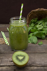 Glass of apple kiwi spinach smoothie with half of kiwi in the foreground - LVF003967