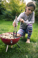 Mädchen beim Grillen von Würstchen und Fleisch im Garten - SARF002204