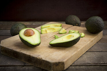 Whole and sliced avocado on wooden board - LVF003979