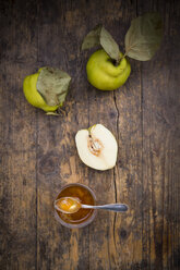 Whole and sliced quinces and a glass of quince jam on wood - LVF003981