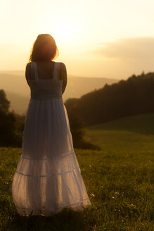 Germany, Baden-Wuerttemberg, Black Forest, back view of woman on Alpine meadow watching sunrise - MIDF000700