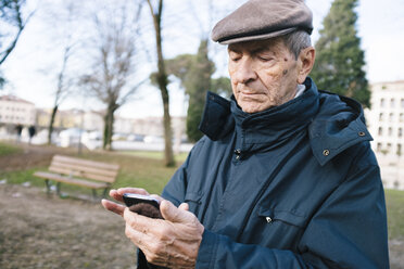 Porträt eines älteren Mannes mit Smartphone in einem Park - GIOF000274