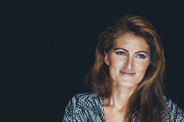 Porträt einer lächelnden Frau mit braunem Haar vor einem schwarzen Hintergrund - CHAF001498