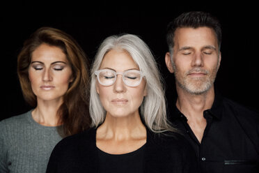Porträt von drei Personen mit geschlossenen Augen vor schwarzem Hintergrund - CHAF001524