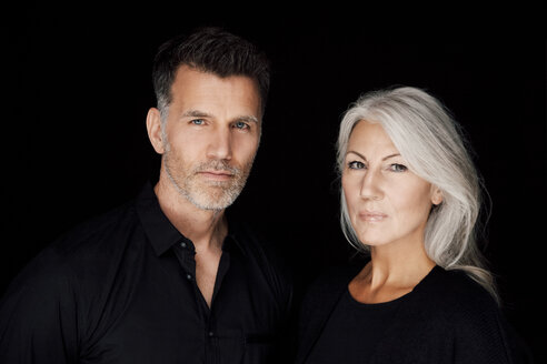 Portrait of mature man and mature woman wearing black clothes in front of black background - CHAF001531