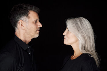 Portrait of mature man and mature woman wearing black clothes in front of black background - CHAF001532