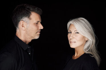 Portrait of mature man and mature woman wearing black clothes in front of black background - CHAF001533