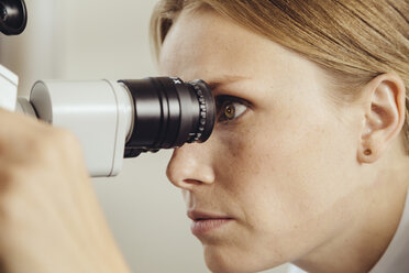 Profil einer Ärztin, die durch ein Operationsmikroskop schaut - MFF002310