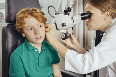 Female doctor examining little boy with microscope - MFF002311
