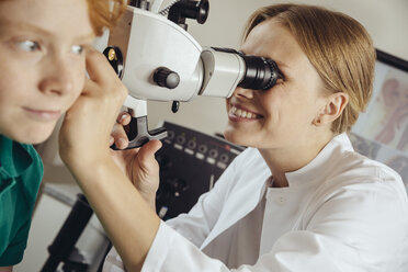 Female doctor examining little boy with microscope - MFF002312