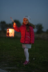 Portrait of smiling little girl with lighted paper lantern on St. Martin's Day at twilight - LBF001247