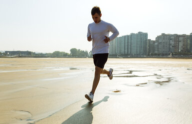 Spain, Asturias, Gijon, young man running on the beach - MGOF000843