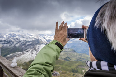 Deutschland, Bayern, Oberstdorf, Seniorin fotografiert mit Handy vom Gipfel des Nebelhorns - FRF000334