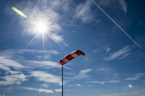 Windsack gegen die Sonne mit Gleitschirm im Hintergrund - FRF000342