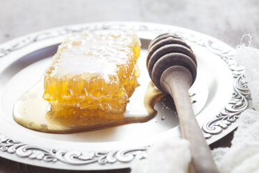 Honeycomb with honey and honey spoon on tin plate - SBDF002346