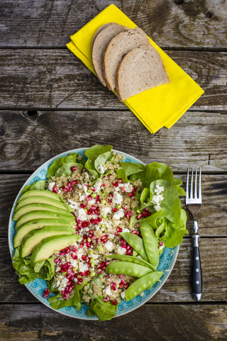 Quinoa-Salat mit Feta, Granatapfel, Avocado und Zuckerschoten auf dem Teller, lizenzfreies Stockfoto