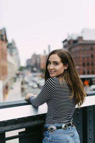 USA, New York City, Porträt einer lächelnden brünetten jungen Frau, lizenzfreies Stockfoto