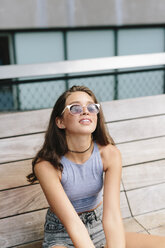 Brunette young woman wearing sunglasses relaxing on bench - GIOF000294