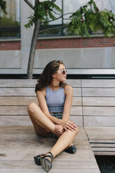 Brunette young woman wearing sunglasses relaxing on bench - GIOF000296