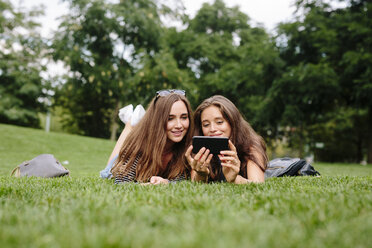 Zwei Freunde in einem Park schauen auf ihr Handy - GIOF000317