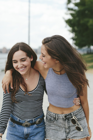 USA, New York City, zwei glückliche Freunde gehen im Freien spazieren, lizenzfreies Stockfoto