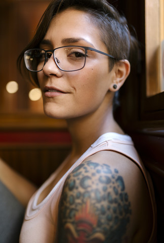 Porträt einer tätowierten jungen Frau mit Nasenpiercing und Brille, lizenzfreies Stockfoto