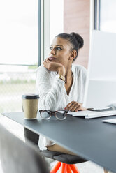 Junge Frau im Büro schaut vom Computerbildschirm weg - UUF005819