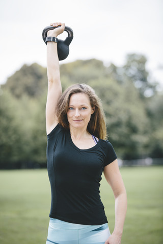 Frau hebt Kettlebell im Park, lizenzfreies Stockfoto