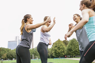 Vier glückliche Frauen, die sich nach einem Workout im Freien die Hände reichen - MADF000538