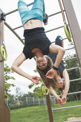 Two women having fun hanging in jungle gym - MADF000547