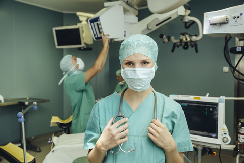 Porträt einer lächelnden Chirurgin im Operationssaal, lizenzfreies Stockfoto